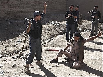 An Afghan police officer throws a disabled man to the ground as journalists look on as they are forced to leave an area of a gunbattle with suspected insurgents in Kabul, Wednesday, Aug. 19, 2009. Afghan authorities have come under criticism for preventing coverage of violent events in the country a day before presidential elections. Gunfire and explosions reverberated through the heart of the Afghan capital Wednesday on the eve of the presidential election after three militants with AK-47s rifles and hand grenades overran a bank. Police stormed the building and killed the three insurgents, officials said. (AP Photo/Kevin Frayer)